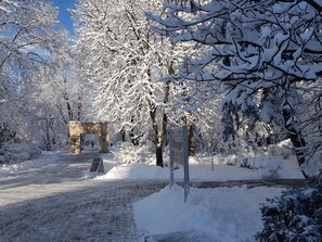 Een sneeuwbedekte pad dat leidt naar een stenen boog in een park.