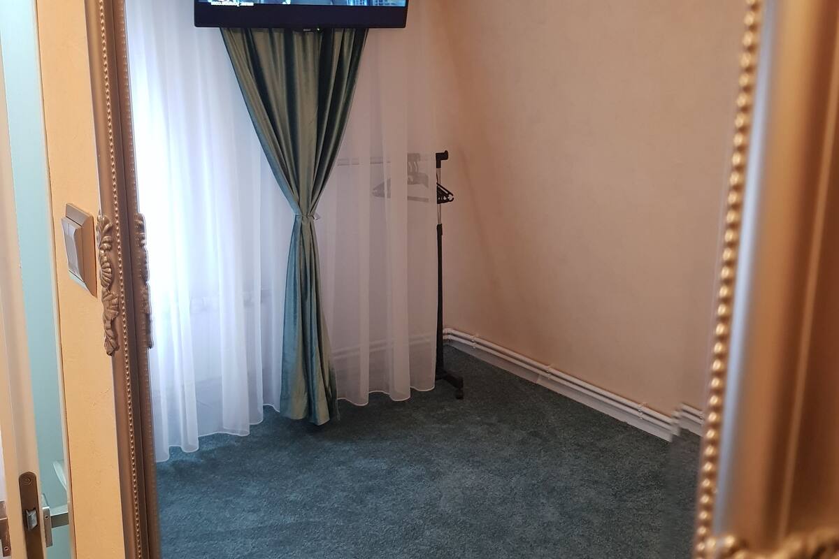 Een kamer met een grote spiegel, een aan de muur bevestigde televisie, een deur en een vloerbedekking.
