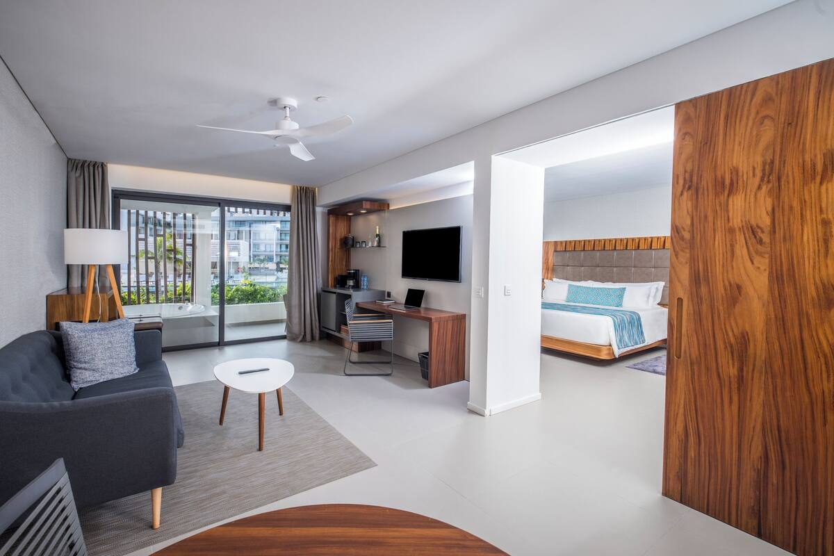 A modern hotel room with a sofa, desk, and bed.