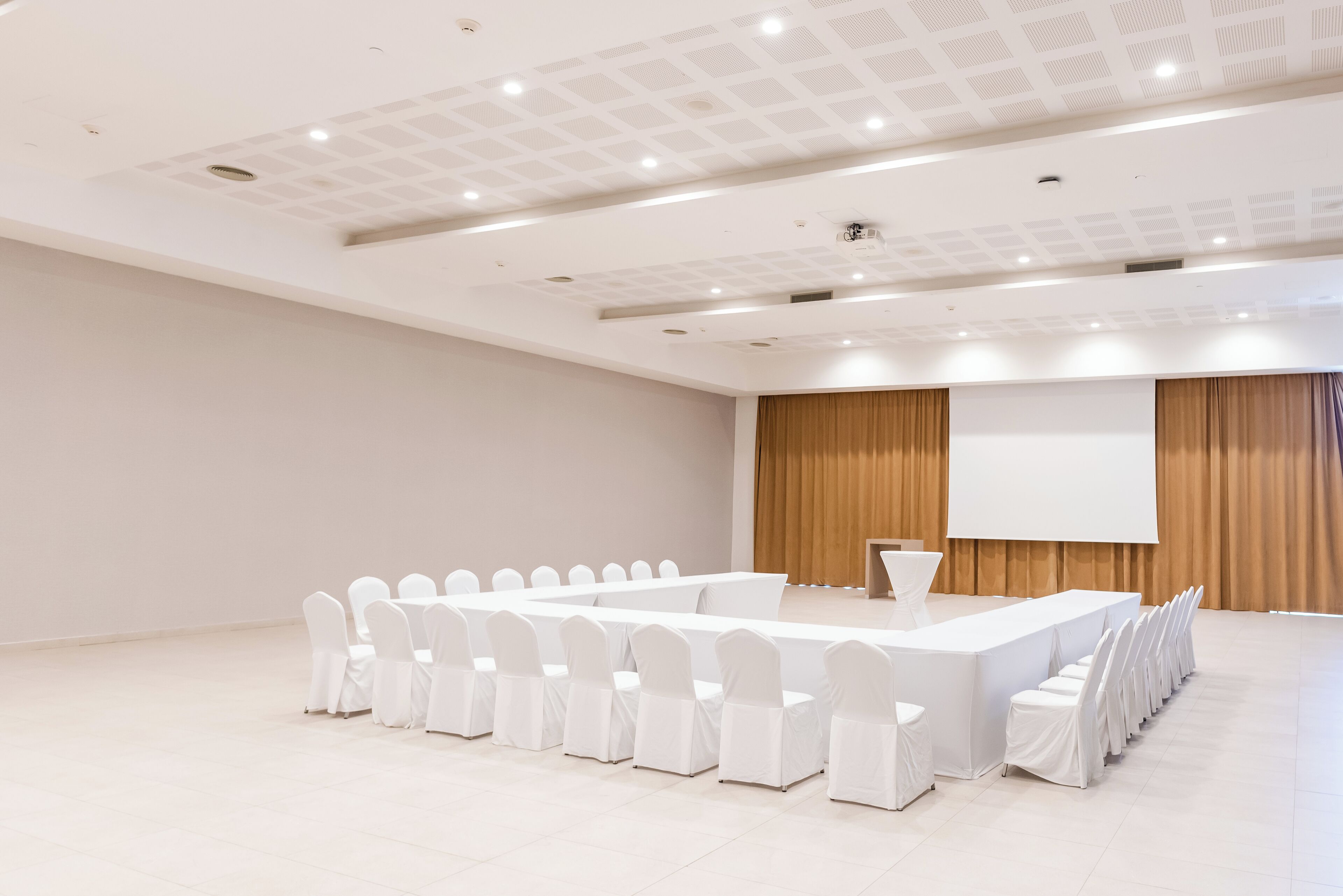 A conference room with a long table and chairs, a projector screen, and a podium.