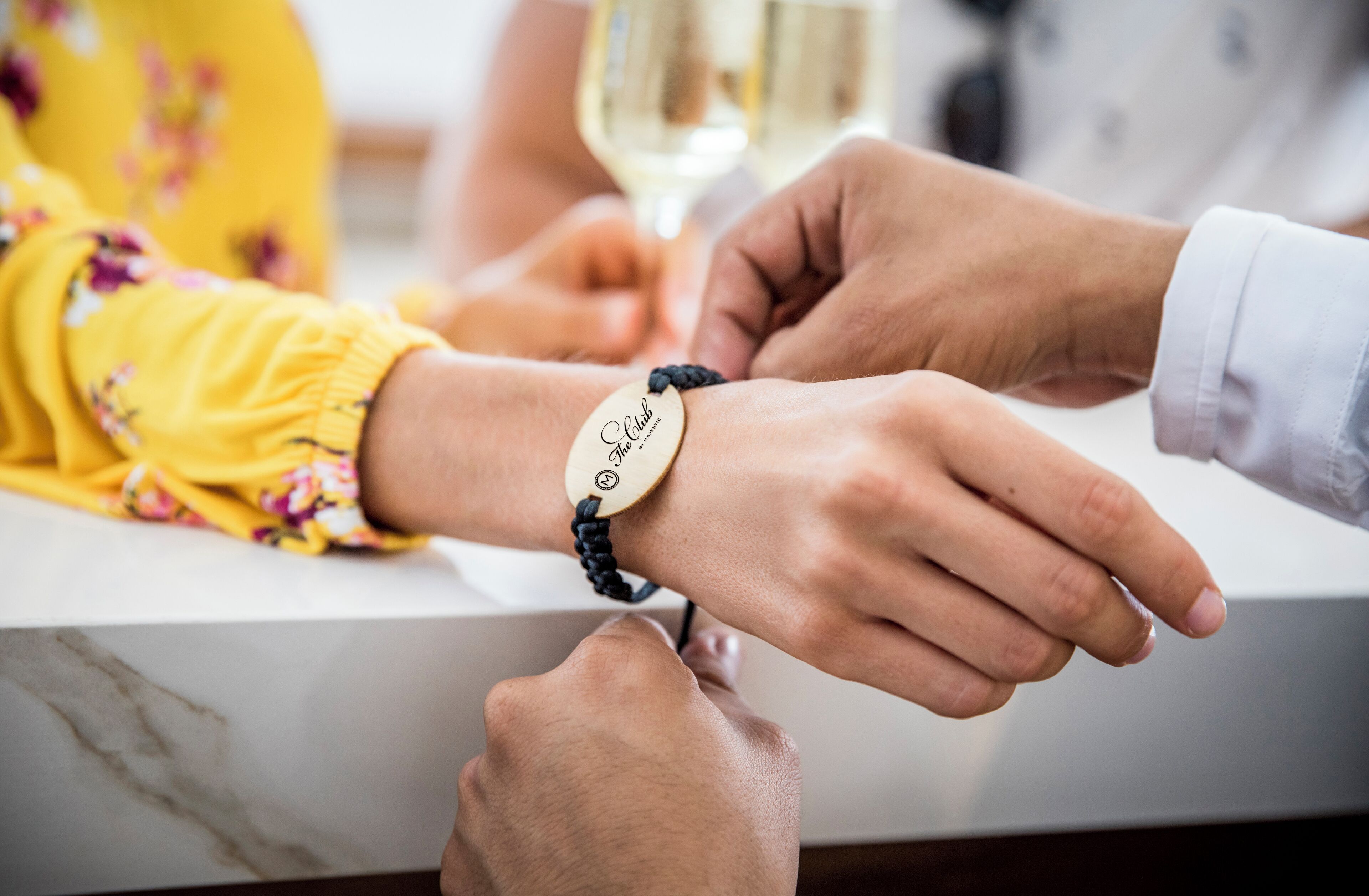 Primer plano de manos con una pulsera y una placa de identificación.