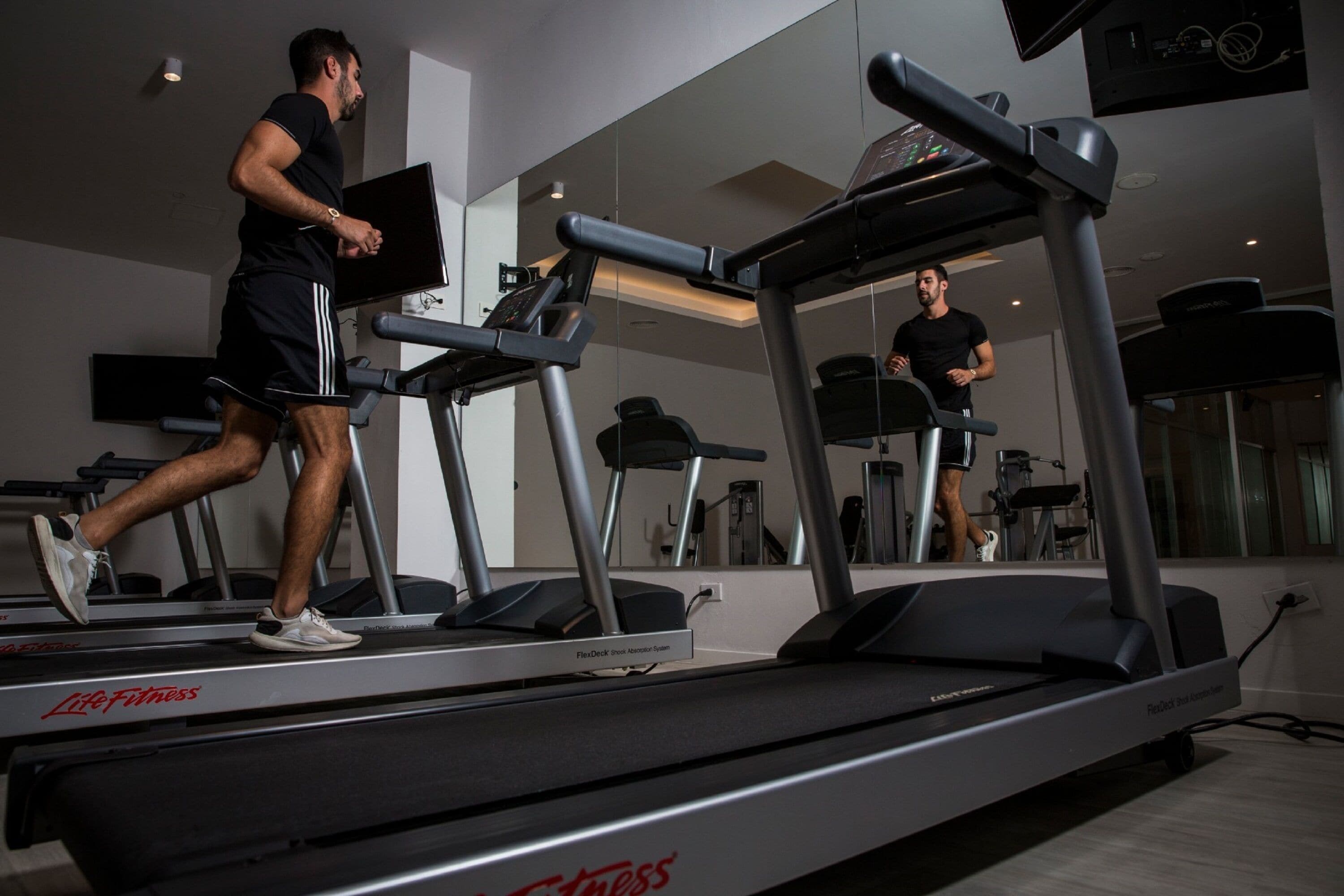 A gym with treadmills and a mirrored wall.