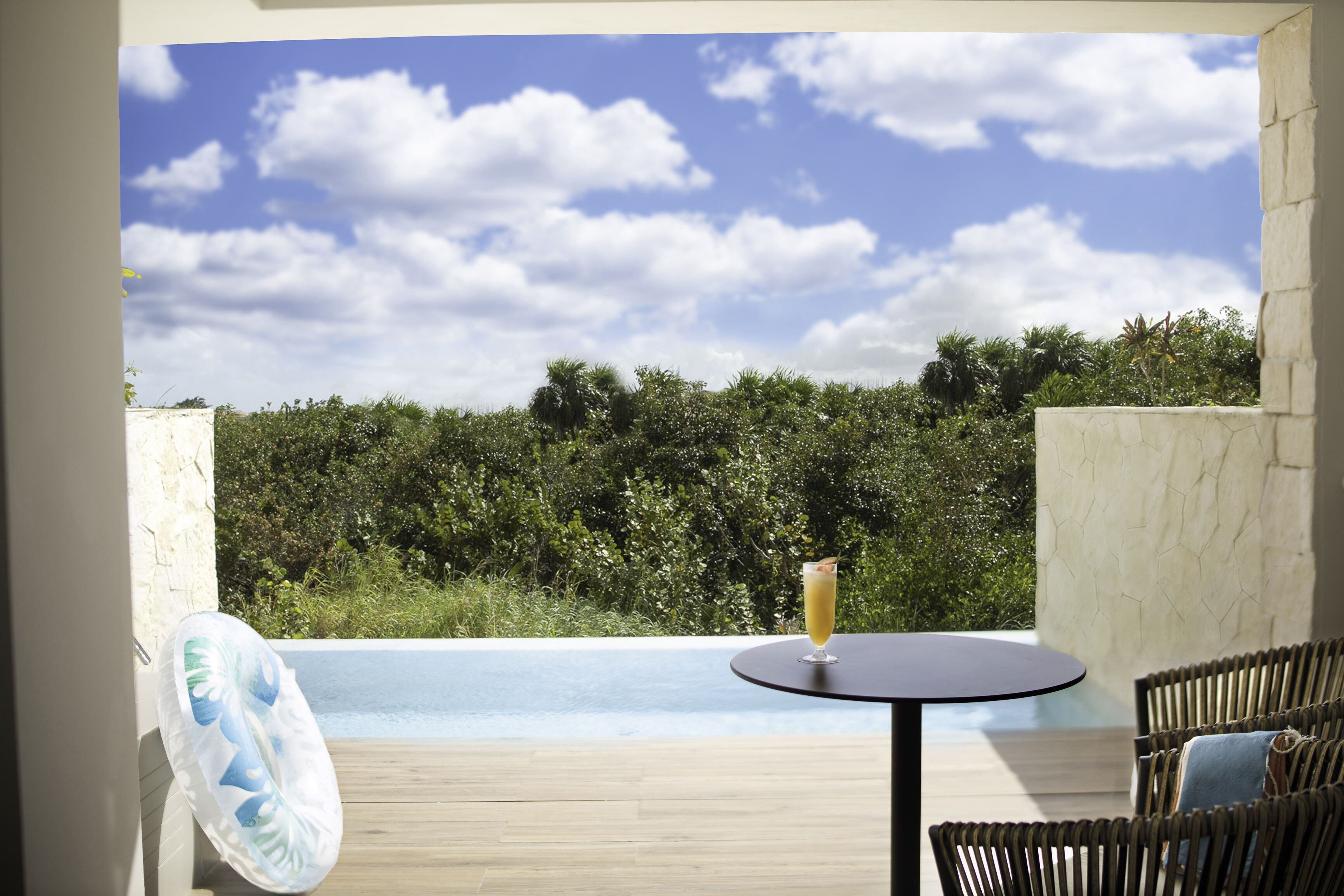 Un balcon avec une piscine, des meubles en osier et un verre à boire.