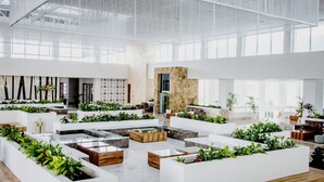 A spacious lobby with white seating areas, planters with greenery, and a modern architectural design. - Majestic Elegance Costa Mujeres – All Inclusive (Costa Mujeres)