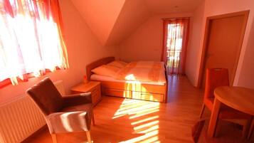 A bedroom with a bed, a chair, a table, and a radiator.