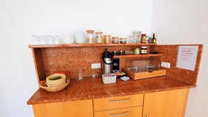 A kitchen counter with a coffee machine, jars of condiments, and a sign in German. - Gästehaus Jäger (Gersfeld)
