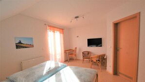 A bedroom with a bed, a desk, a chair, a television, and a door. - Gästehaus Jäger (Gersfeld)