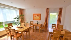 A dining area with wooden furniture, a potted plant, and a painting on the wall. - Gästehaus Jäger (Gersfeld)