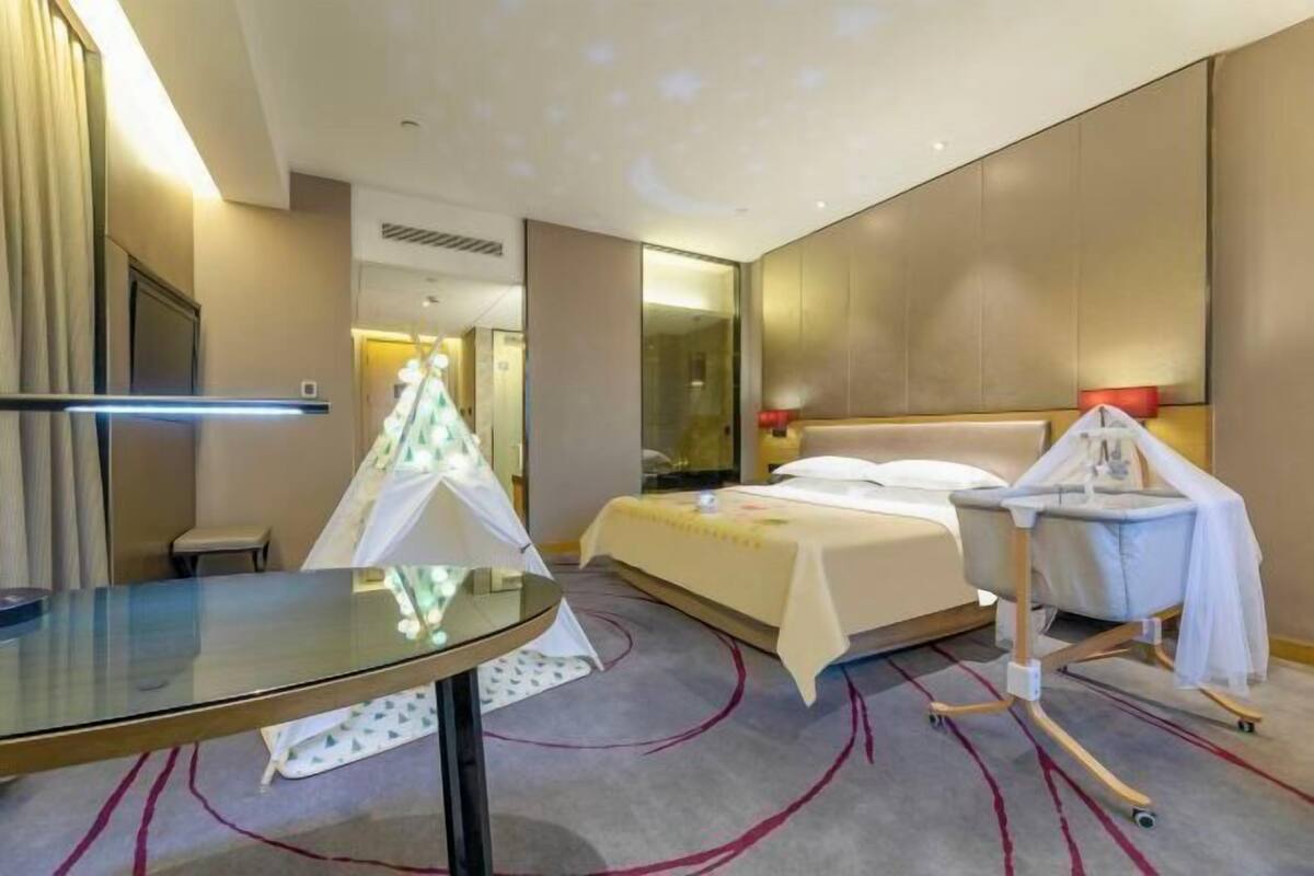 Ein Hotelzimmer mit Bett, Glastisch, Wickelmöglichkeit und Spiegel.
