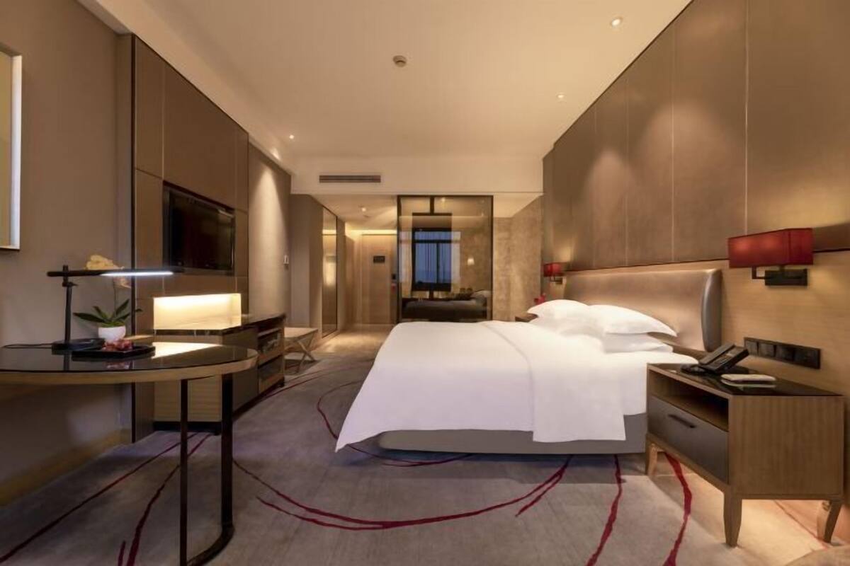 Ein modernes Hotelzimmer mit einem großen Bett, Nachttischen, einem Schreibtisch und einem Fernseher.