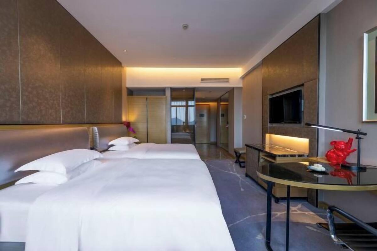 Ein modernes Hotelzimmer mit einem großen Bett, einem Schreibtisch, einem Fernseher und einem Badezimmer.