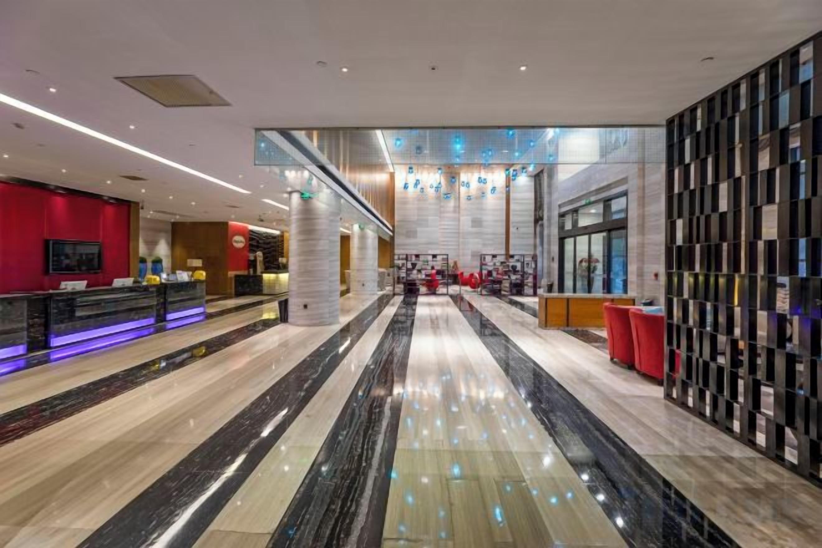 A hotel lobby with a marble floor, reception desk, and a modern light fixture.