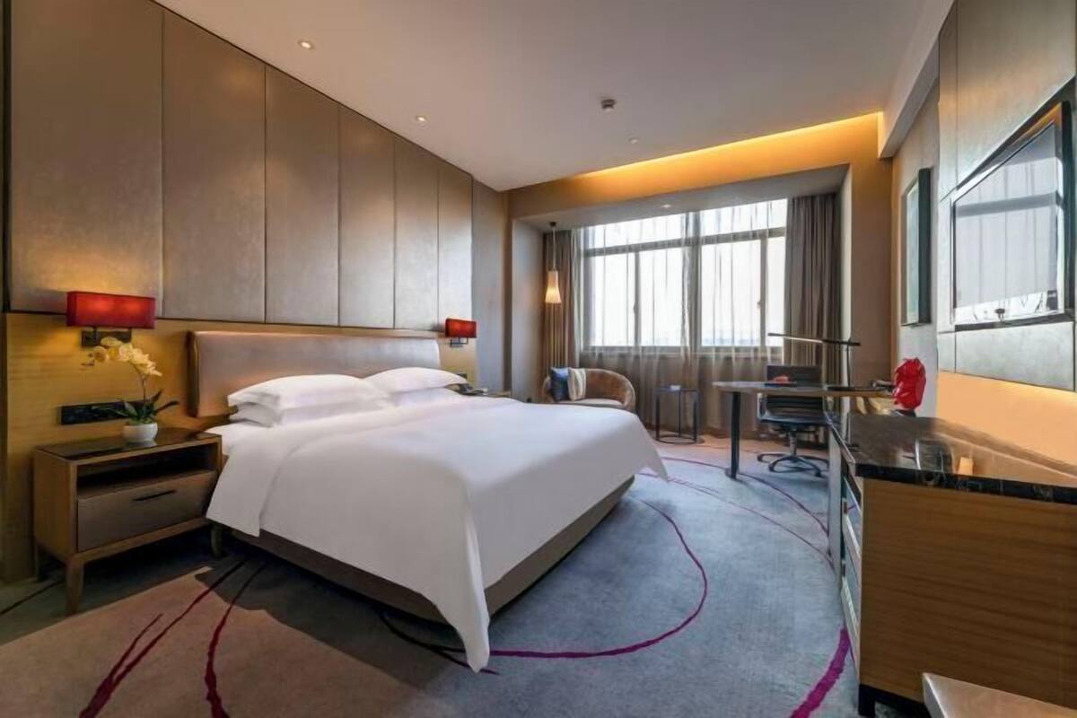 Ein modernes Hotelzimmer mit einem großen Bett, einem Schreibtisch und einem Sessel.