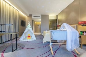 A hotel room with a bed, a bedside table, a lamp, a window, a wall-mounted TV, and a small play area with a tent and Winnie the Pooh. - 3b Hotel (Yuyao Shengshan) (Yuyao)