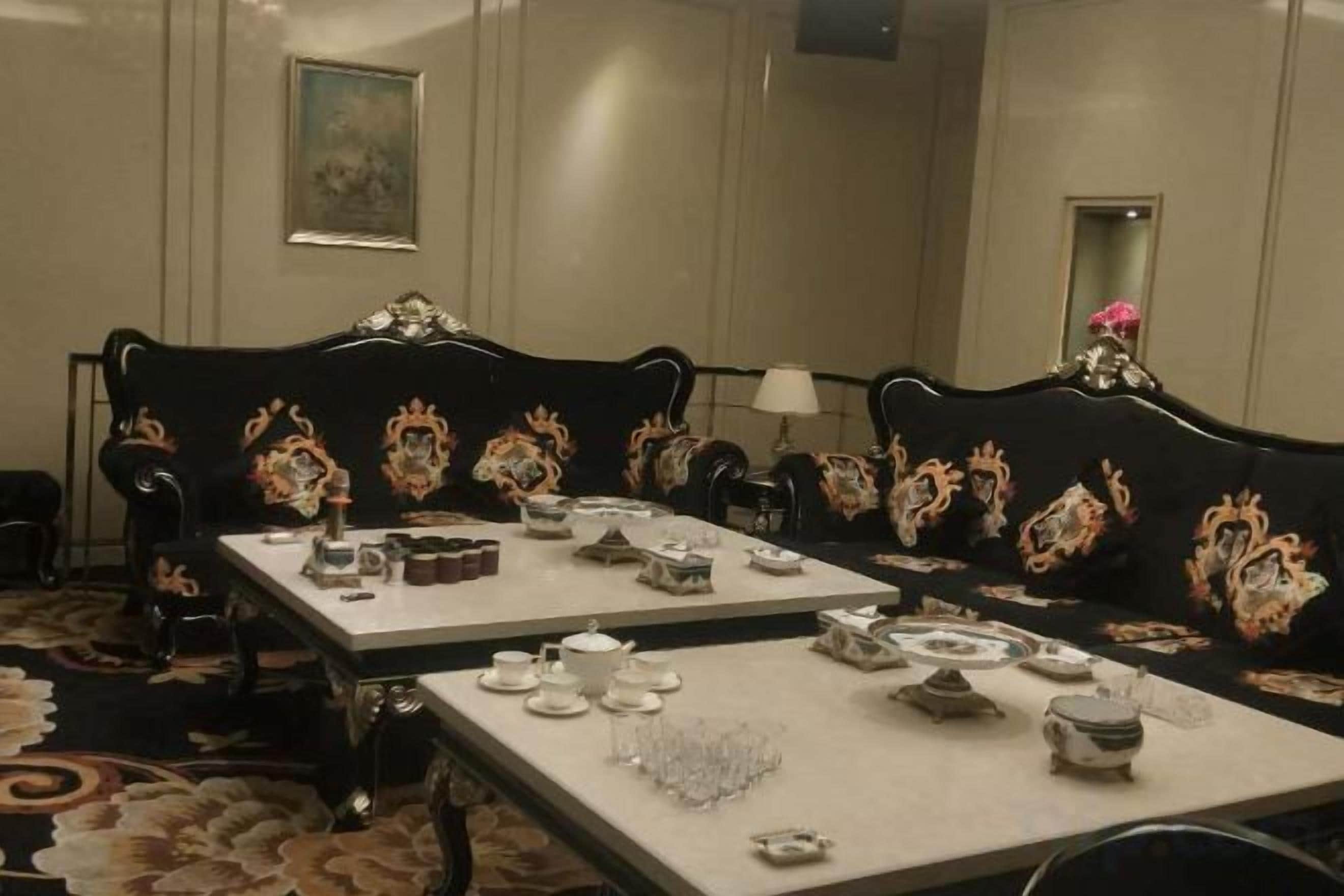 A formal dining room with ornate furniture, a chandelier, and a painting on the wall.