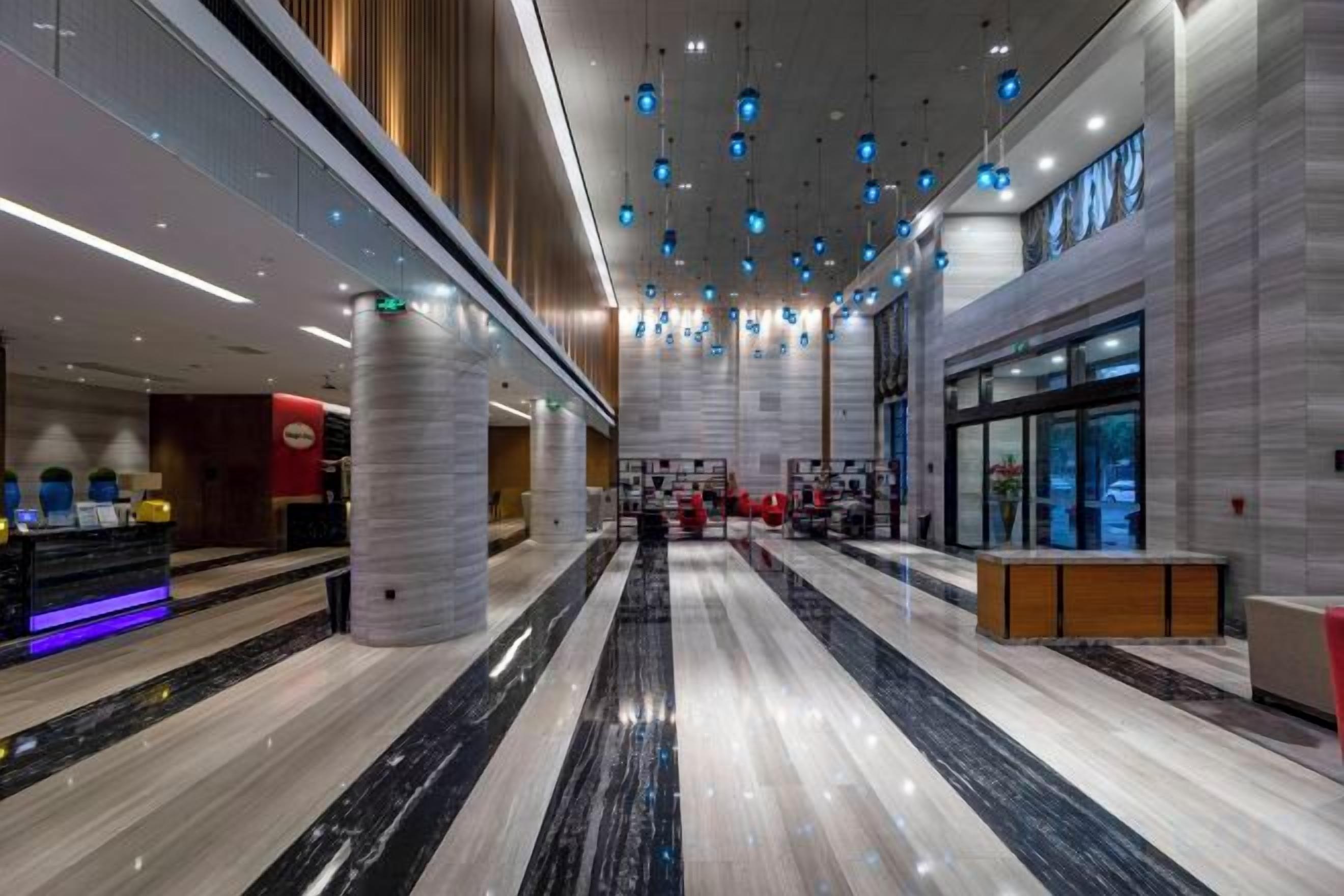 A spacious lobby with a marble floor, a reception desk, and a modern ceiling design.