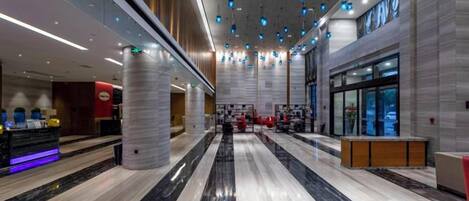 Un hall espacioso con piso de mármol, una recepción y un diseño moderno en el techo.