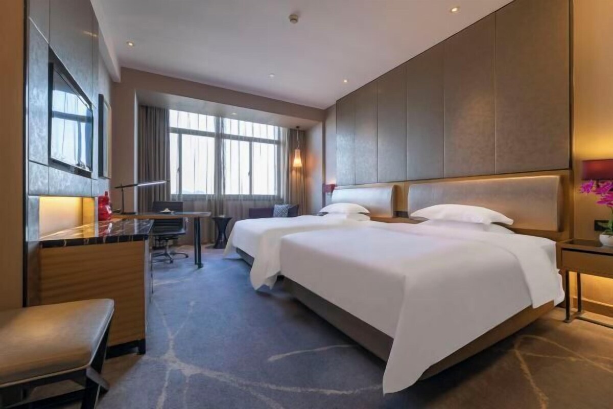 A hotel room with two beds, a desk, and a chair.