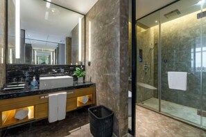 A modern bathroom with a large mirror, a marble countertop, and a glass-enclosed shower.