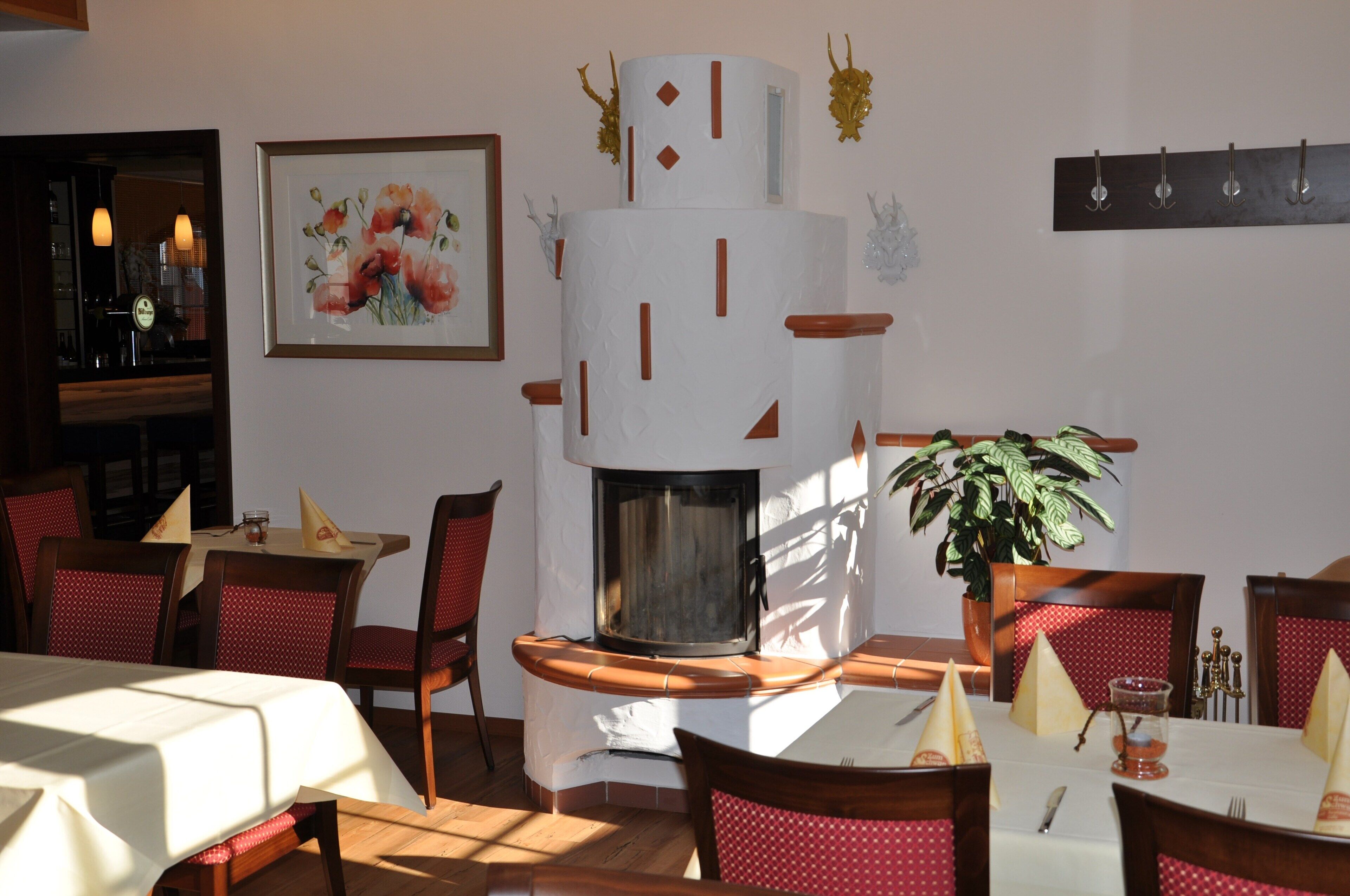 Ein Restaurant mit einem zentralen Kamin, roten Sitzmöbeln und einem gedeckten Tisch.