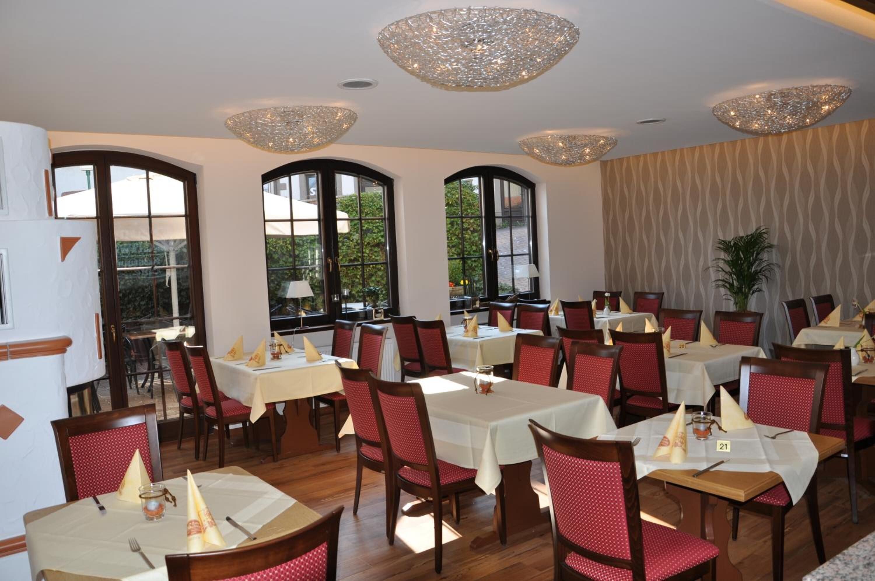 Un espace repas avec des tables et des chaises, de grandes fenêtres et des luminaires décoratifs au plafond.