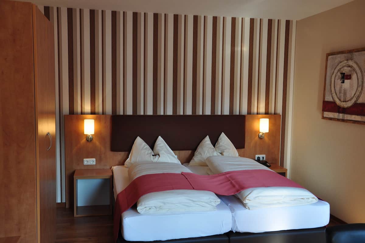 A double bed with a wooden headboard, two bedside tables with lamps, and a striped wall panel.