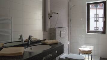 Un baño moderno con lavamanos, espejo, toallero y retrete.