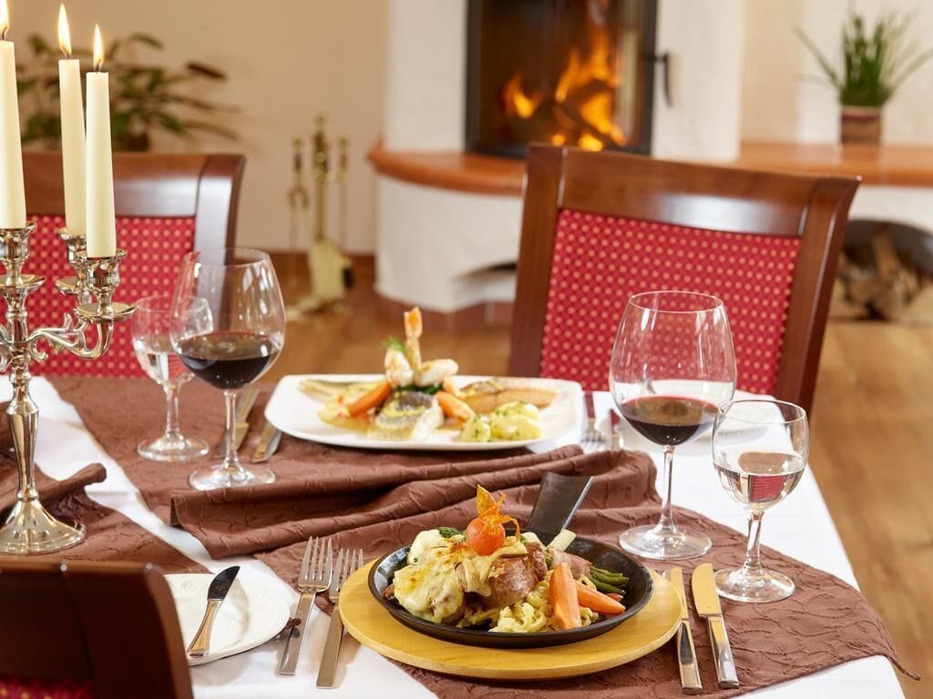 A dining table set with plates of food, wine glasses, and a candelabra.