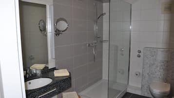 A modern bathroom with a glass-enclosed shower, a sink with a mirror, and a toilet.