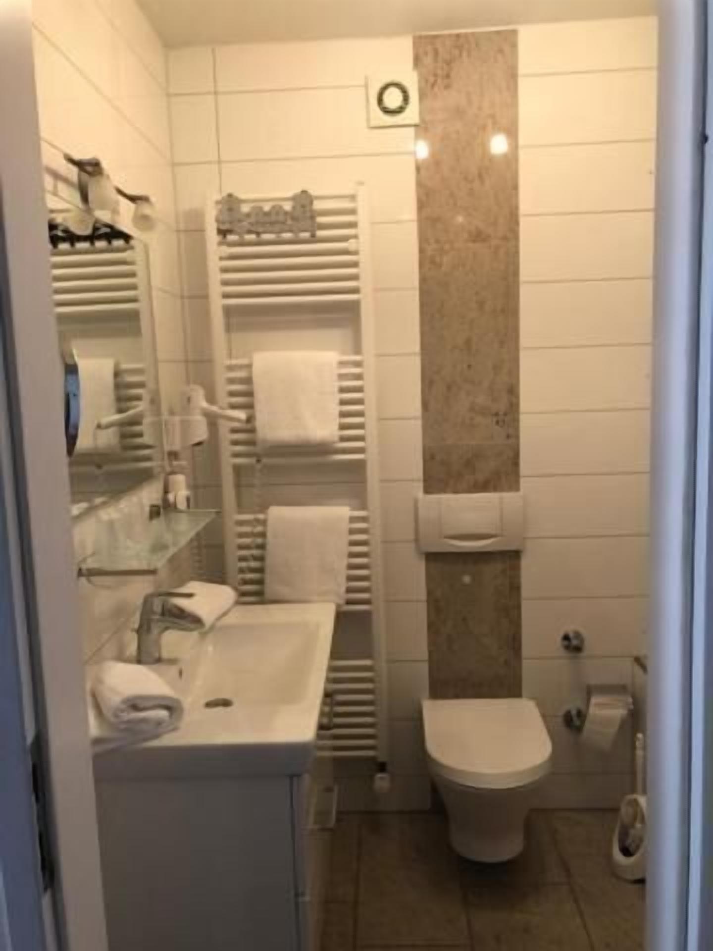 A modern bathroom with a toilet, sink, and towel rack.