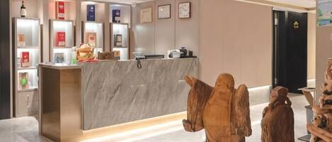 A reception desk with a marble counter, a small statue of an angel, and a wooden sculpture.