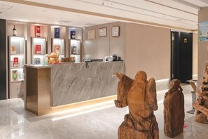 Una recepción con mostrador de mármol, una pequeña estatua de un ángel y una escultura de madera.