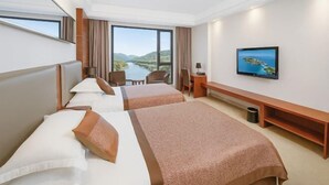 A hotel room with two beds, a TV, a desk, and a view of a river and hills. - Victoria Royal Hotel (Shangrao)