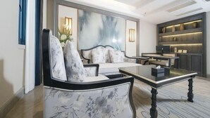 A modern living room with a sofa, a coffee table, and a bookshelf. - Victoria Royal Hotel (Shangrao)