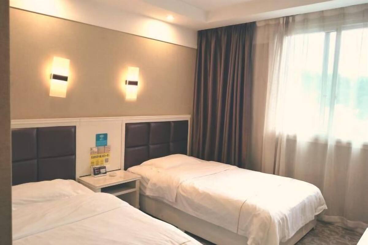 Une chambre d’hôtel avec deux lits, une table de chevet et deux lampes fixées au mur.
