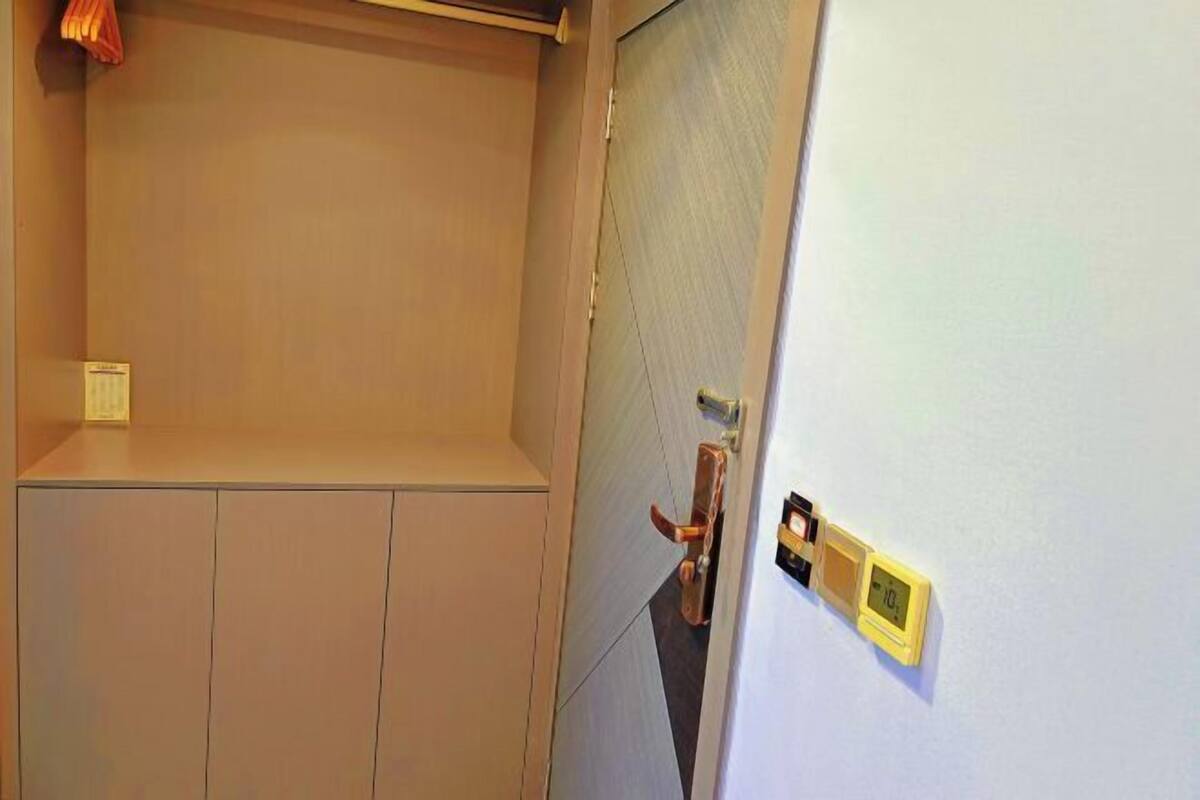 Une pièce avec une porte fermée, un interrupteur et un thermostat au mur.