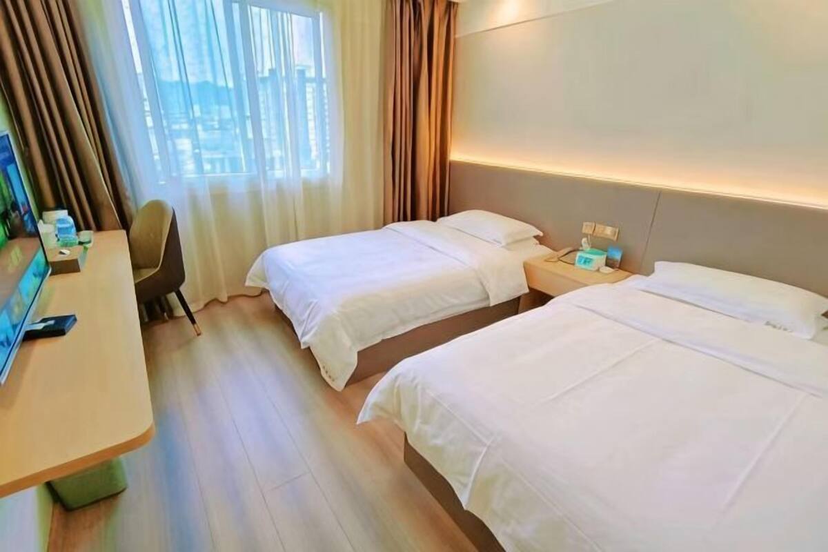 Une chambre d’hôtel avec deux lits, un bureau, une chaise et un téléviseur.