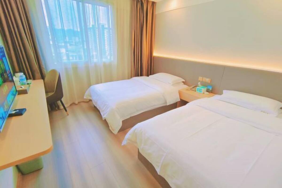 Une chambre d’hôtel avec deux lits, un bureau et une chaise.