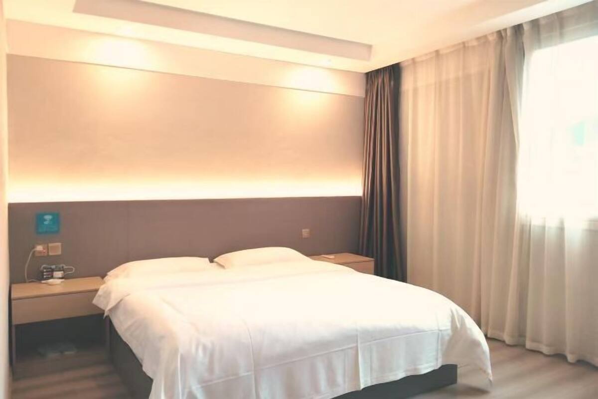 Une chambre d’hôtel avec un lit, une table de chevet et une fenêtre avec des rideaux.