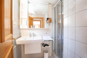 A bathroom with a white sink, mirror, and a glass shower enclosure.