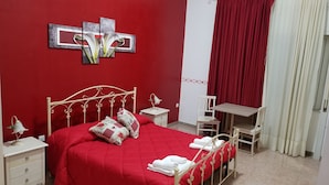 Ein rot eingerichtetes Schlafzimmer mit Bett, Nachttischen, Schreibtisch und Stuhl.