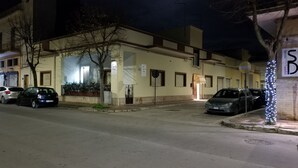 Ein Gebäude mit einem ehrfurchtgebietenden Eingang, geparkten Autos und einer Straßenlaterne.