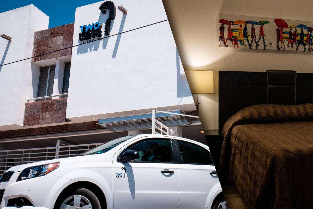 A white car parked in front of a building with a sign reading "TWO KEYS RESTAURANT DRIVE".
