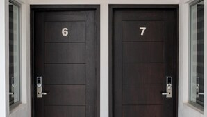 Deux portes en bois sombre, portant les numéros 6 et 7, chacune dotée d’une poignée de porte moderne et d’une petite fenêtre au-dessus.