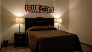 Une chambre à coucher avec un grand lit, deux tables de chevet et une œuvre d’art accrochée au mur au-dessus du lit.