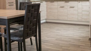 Une cuisine moderne avec des meubles de couleur bois clair, un réfrigérateur en acier inoxydable et un four à micro-ondes encastré.