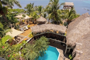 Un resort con piscina, construcciones de techo de paja y palmeras.
