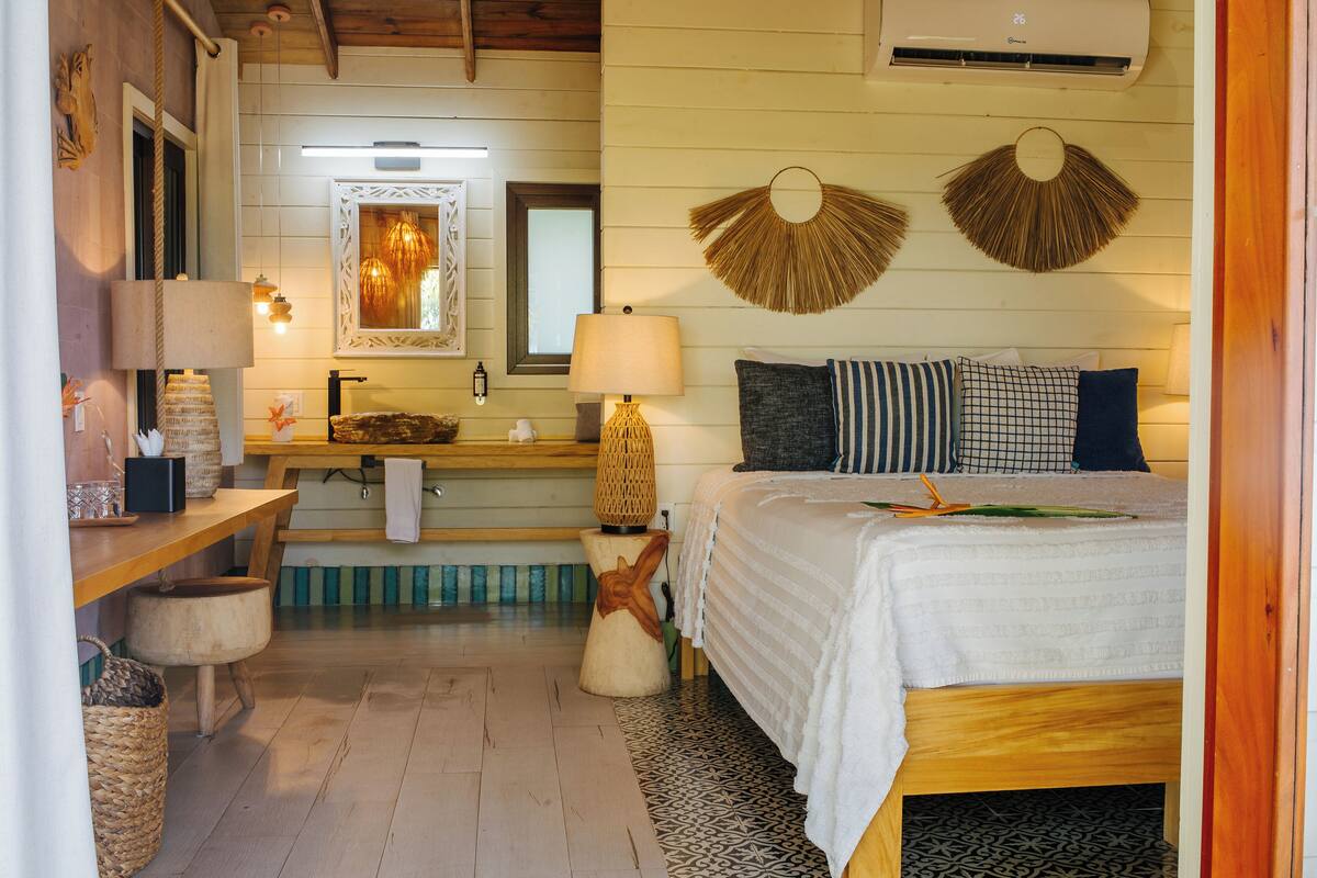 A bedroom with a bed, bedside table, lamp, and wall decor.