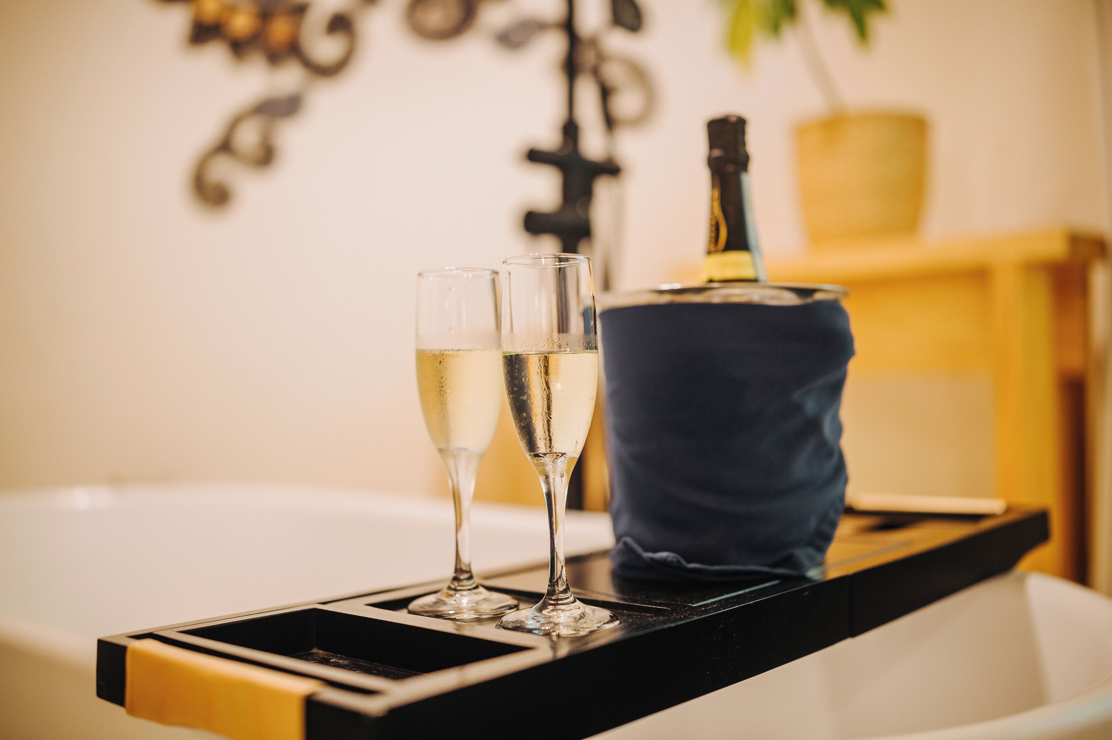A tray with two glasses of champagne and a bottle on a table.