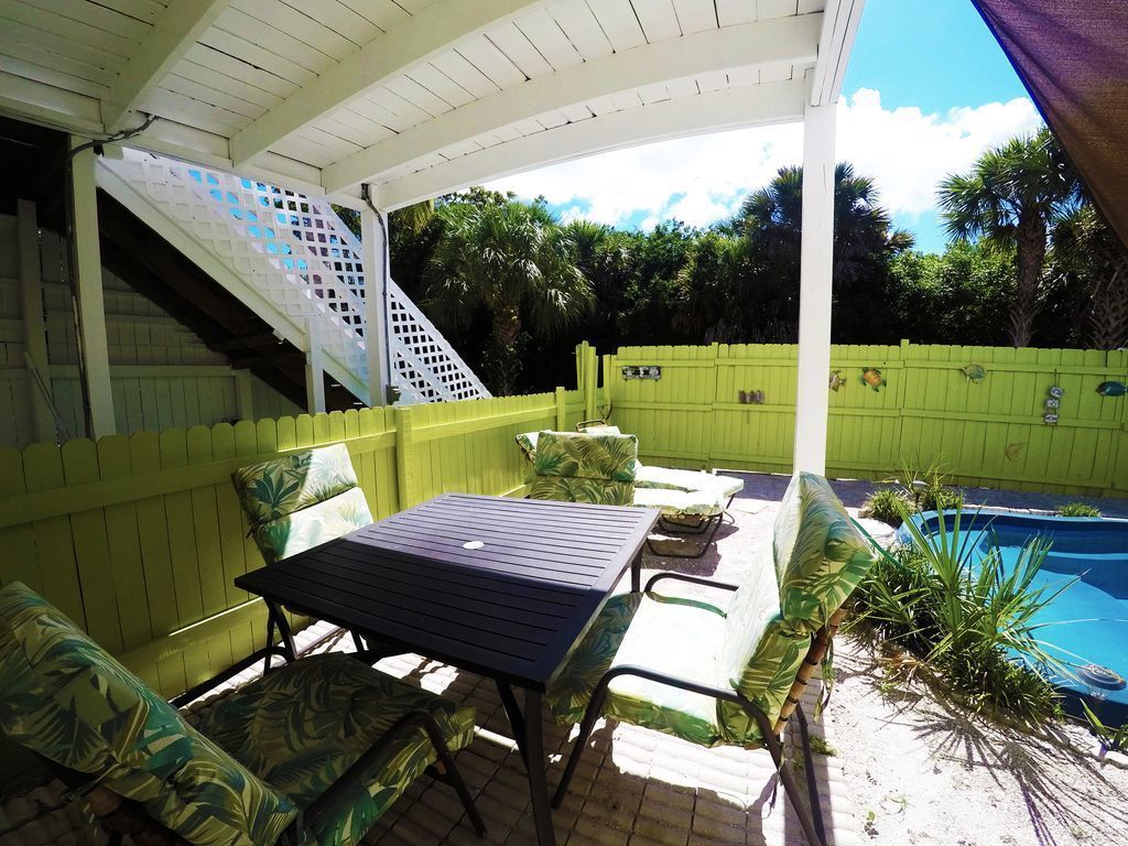 Un patio cubierto con piscina, mobiliario exterior y una escalera que lleva a un nivel superior.